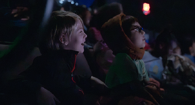 Two school age boys laugh while watching a performance at Starlight.